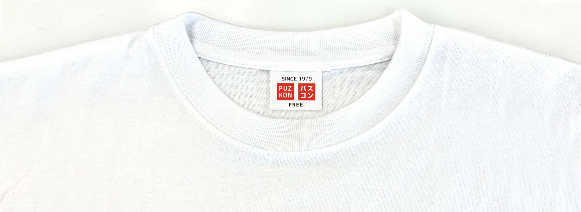 パズコンのロゴ入りタグが付いた白いTシャツ